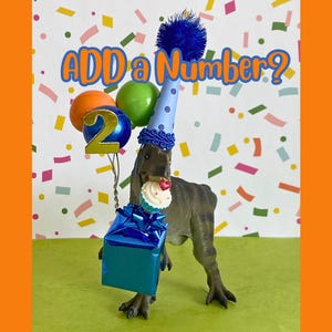 May include: A brown dinosaur figurine wearing a blue polka-dot party hat with a blue pom-pom. It holds a blue gift box, a cupcake, and a cluster of balloons with a gold number 2. The text ADD a Number? is displayed above the dinosaur.