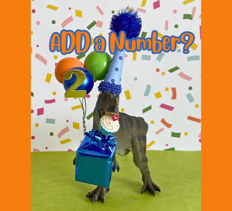 May include: A brown dinosaur figurine wearing a blue polka-dot party hat with a blue pom-pom. It holds a blue gift box, a cupcake, and a cluster of balloons with a gold number 2. The text ADD a Number? is displayed above the dinosaur.