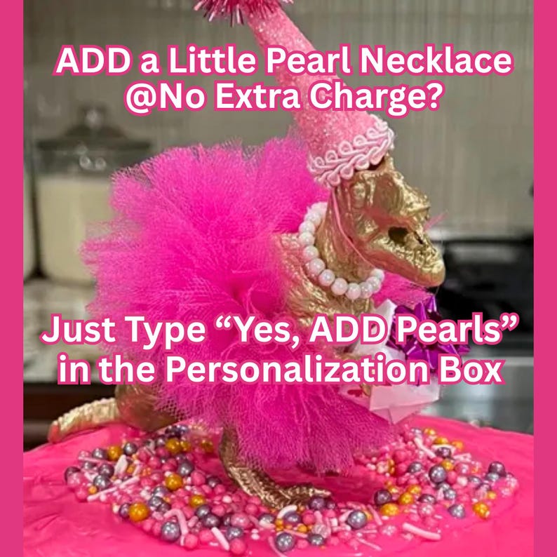 May include: A gold-colored dinosaur figurine wearing a bright pink tulle tutu, a matching pink party hat with a pom-pom, and a white pearl necklace. The text reads: ADD a Little Pearl Necklace @No Extra Charge? Just Type &ldquo;Yes, ADD Pearls&rdquo; in the Personalization Box.