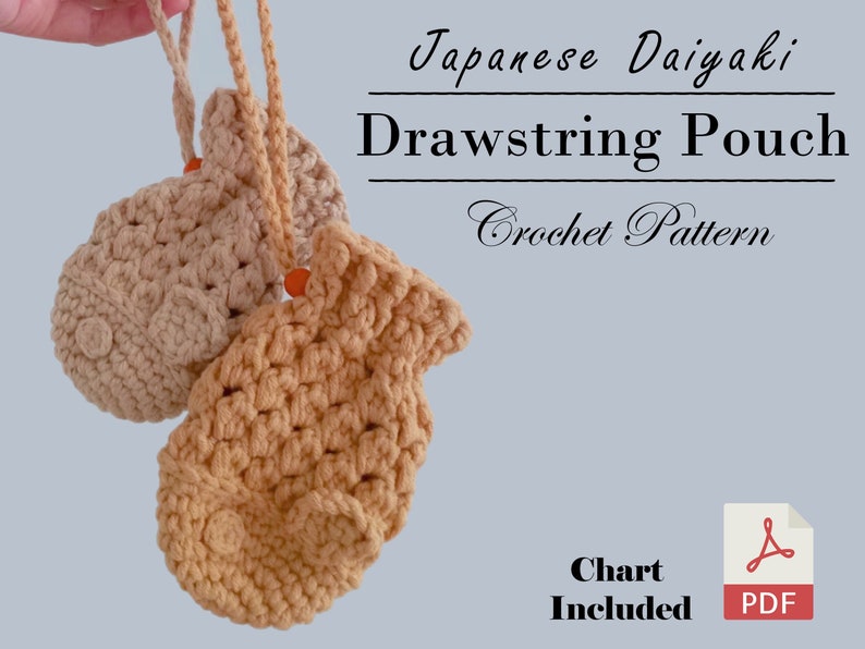 May include: Two crocheted drawstring pouches in beige and light brown, shaped like Japanese Taiyaki fish cakes. The pouches are hanging from a string and the text "Japanese Taiyaki Drawstring Pouch Crochet Pattern" is above them. The text "Chart Included" and a PDF icon are below the pouches.