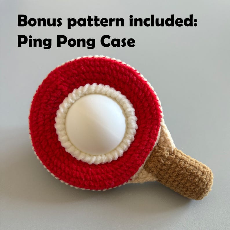 May include: A crocheted ping pong paddle with a red and white circular design and a brown handle. The text "Bonus pattern included: Ping Pong Case" is at the top of the image.