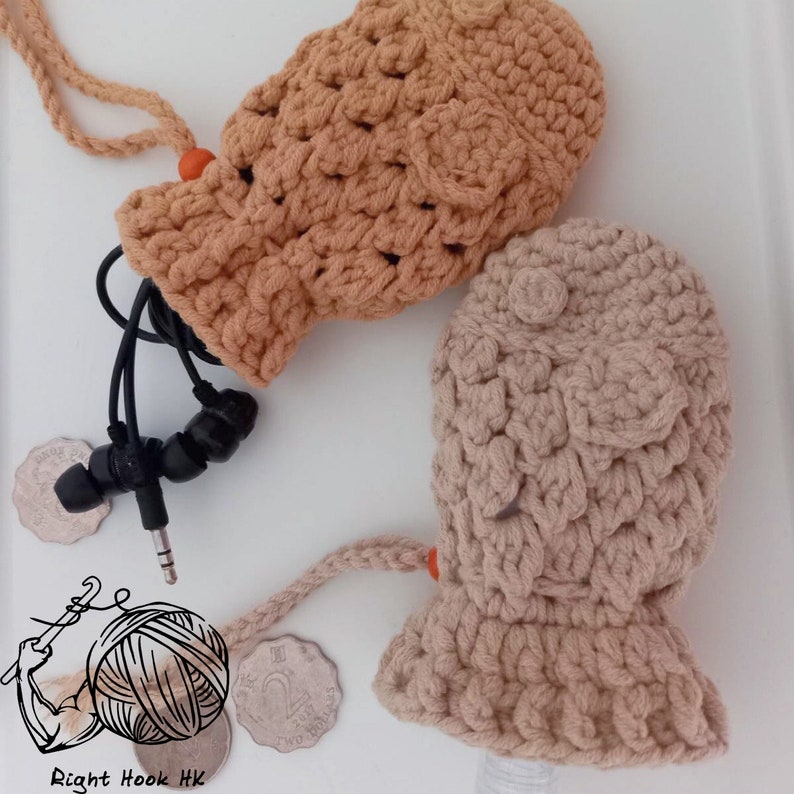 May include: Two crocheted fish-shaped pouches in beige and brown with orange accents. The pouches are made with a textured stitch and have a drawstring closure. The pouches are filled with black headphones.