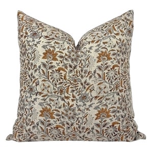 May include: A decorative cushion with a floral pattern in shades of brown, grey, and white on a beige background.
