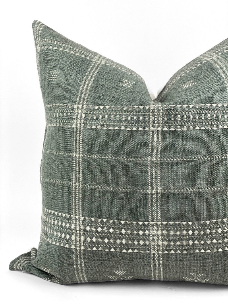 May include: A green and white patterned throw pillow with a woven texture. The pillow has a square shape and a subtle geometric design.
