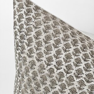 May include: Close-up of a white pillow with a brown floral pattern. The pattern is a repeating design of small flowers and leaves.