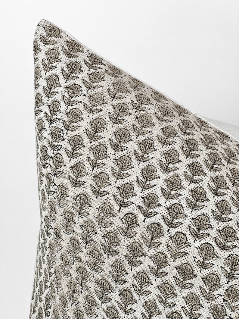 May include: Close-up of a white pillow with a brown floral pattern. The pattern is a repeating design of small flowers and leaves.