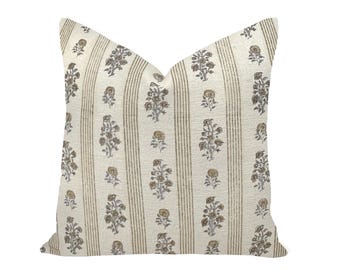 May include: A square throw pillow featuring an off-white base fabric with vertical tan stripes. The design includes a repeating pattern of small, brown floral motifs arranged in columns between the stripes, creating a balanced and textured appearance.