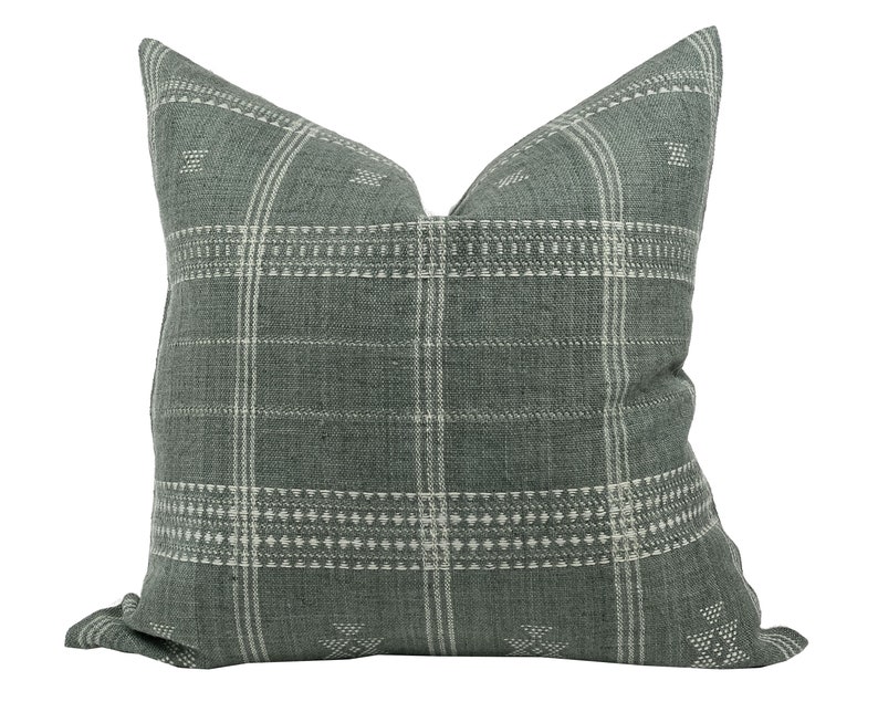 May include: A green and white plaid cushion with a geometric pattern. The cushion is made of a soft, textured fabric.