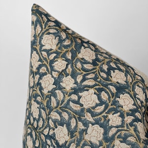 May include: A decorative throw pillow with a blue and gold floral pattern. The pillow is made of a soft, textured fabric.