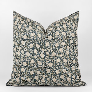 May include: A teal blue throw pillow with a white floral pattern. The pillow has a square shape and is made of a soft fabric.