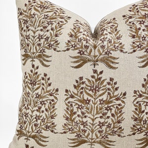May include: A beige linen pillow with a brown floral pattern. The pillow has a square shape and a subtle texture.