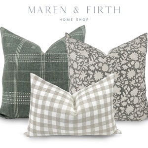 May include: Three decorative throw pillows. One pillow is green with a white plaid pattern. One pillow is beige with a white floral pattern. One pillow is beige with a white and black gingham pattern.
