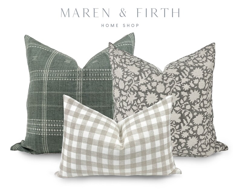 May include: Three decorative throw pillows. One pillow is green with a white plaid pattern. One pillow is beige with a white floral pattern. One pillow is beige with a white and black gingham pattern.