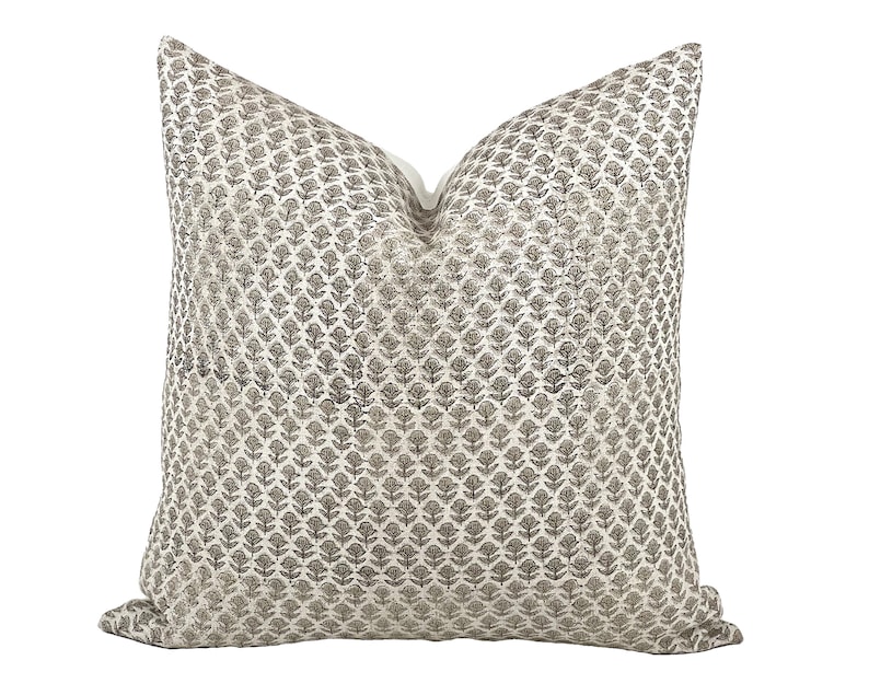 May include: A white throw pillow with a brown floral pattern. The pillow is made of a soft, textured fabric.