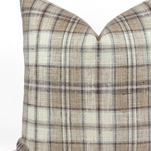 May include: A brown, beige, and white plaid throw pillow with a square shape.
