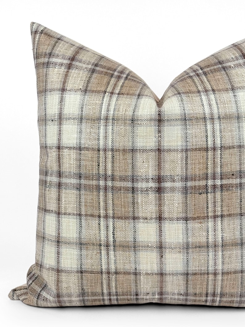 May include: A brown, beige, and white plaid throw pillow with a square shape.