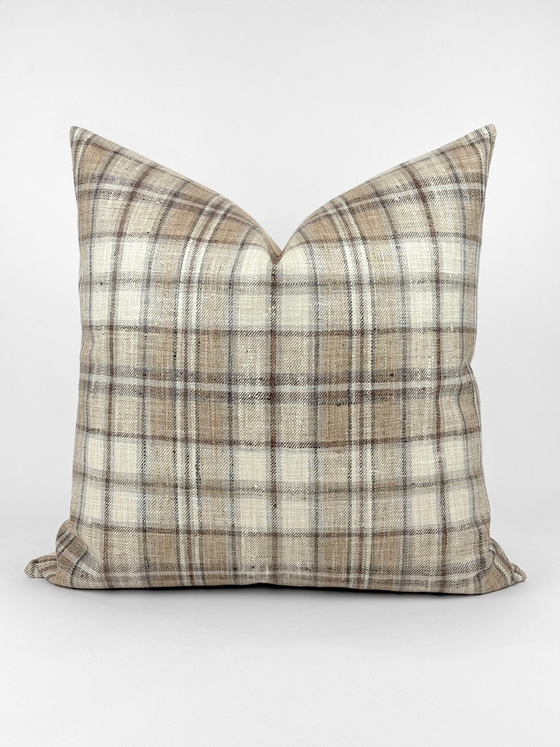 May include: A brown and white plaid throw pillow with a square shape.