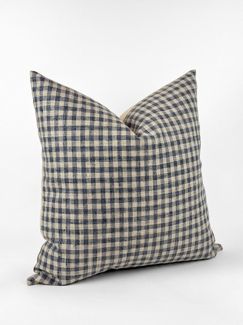 May include: A blue and white gingham throw pillow with a square pattern. The pillow is made of a soft, textured fabric.