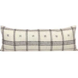 May include: A long, rectangular white pillow with a black and white geometric pattern. The pillow is made of a soft, woven fabric.