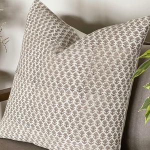 May include: A white throw pillow with a brown floral pattern. The pillow is made of a soft, linen-like fabric and has a subtle sheen.