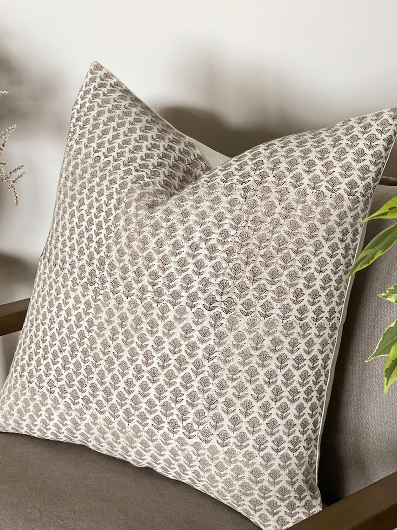 May include: A white throw pillow with a brown floral pattern. The pillow is made of a soft, linen-like fabric and has a subtle sheen.