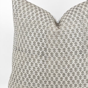 May include: A square throw pillow with a white background and a repeating pattern of small black floral designs.