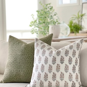May include: Two decorative throw pillows, one with a green floral pattern and the other with a white background and a pink and gray floral pattern.