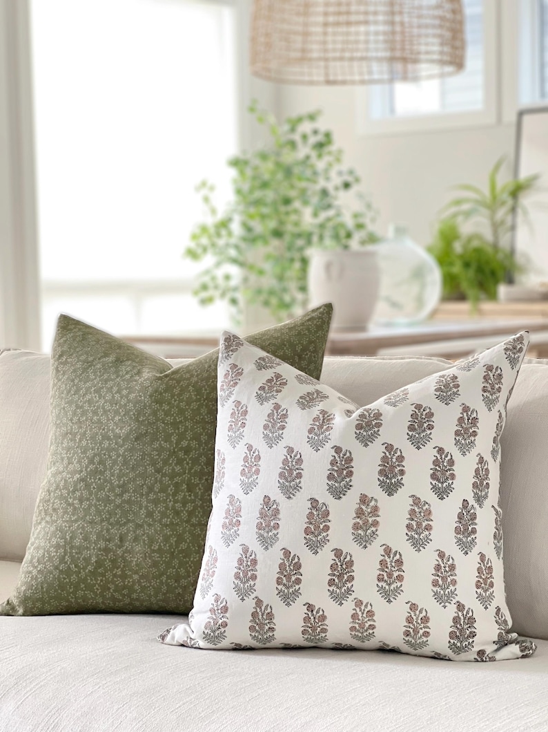 May include: Two decorative throw pillows, one with a green floral pattern and the other with a white background and a pink and gray floral pattern.
