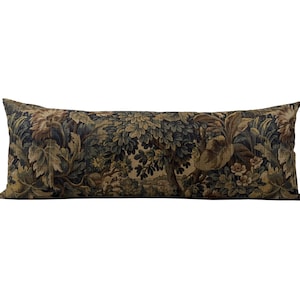 May include: A long, rectangular decorative pillow with a tapestry design. The pillow features a detailed forest scene in shades of green, brown, and gold. The fabric has a textured appearance, adding depth to the design. The pillow is designed for decorative use.