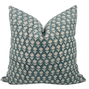 May include: Teal blue throw pillow with a white floral pattern.