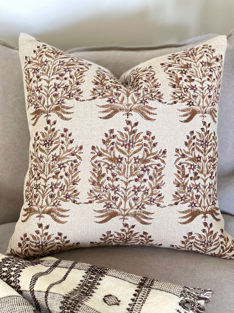 May include: A beige throw pillow with a brown floral pattern. The pillow is made of linen and has a subtle texture.