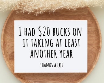 May include: A white card with black text that reads "I had $20 bucks on it taking at least another year. Thanks a lot." The card is sitting on a wooden plate.
