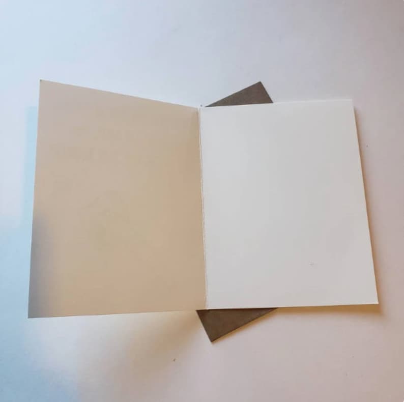 May include: A blank white card with a brown envelope. The card is folded in half and the envelope is tucked into the fold.