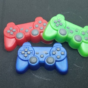 May include: Three plastic toy game controllers in red, green, and blue. The controllers are shaped like a traditional video game controller with buttons and a directional pad.