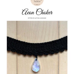 May include: A black crocheted choker necklace with a teardrop-shaped iridescent gemstone pendant. The choker is on a wooden surface.  Aeon Choker. Pattern by Alethea Handmade.