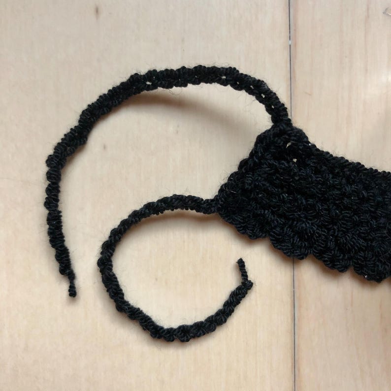 May include: A black crocheted headband with a loose end of yarn.