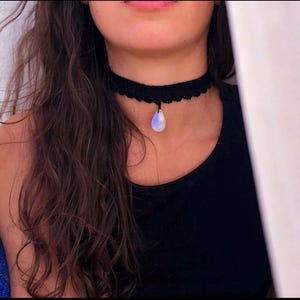 May include: A black crocheted choker necklace with a teardrop-shaped moonstone pendant.