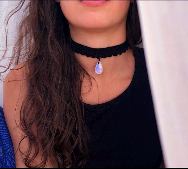 May include: A black crocheted choker necklace with a teardrop-shaped moonstone pendant.