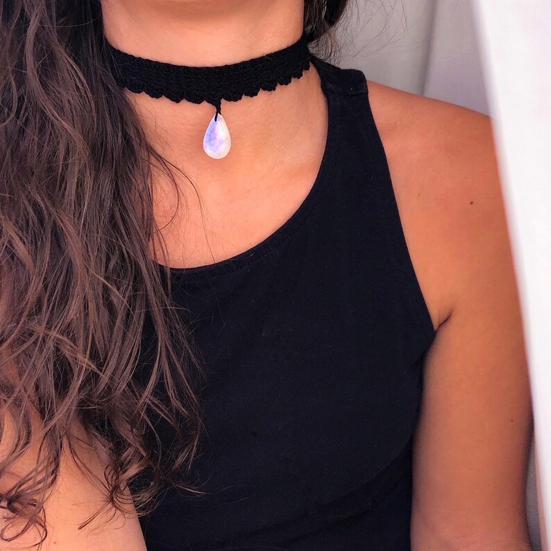 May include: A black crocheted choker necklace with a teardrop-shaped iridescent gemstone pendant.