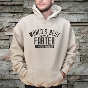 May include: A beige hoodie with a black graphic that says "World's Best Farter I Mean Father" with three stars.