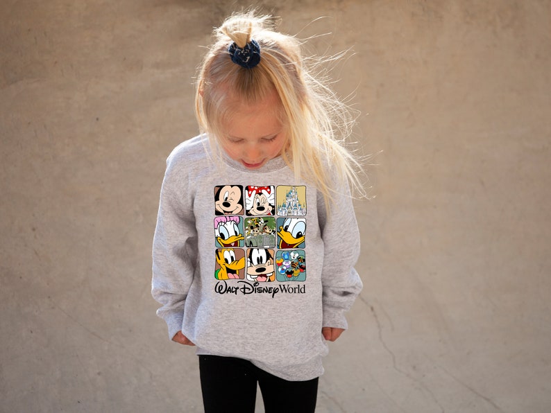 Op de afbeelding: Een grijs longsleeve sweatshirt met een kleurrijke afbeelding van Mickey Mouse, Minnie Mouse, Donald Duck, Goofy en het kasteel van Assepoester. De tekst "Walt Disney World" staat onder de afbeelding.