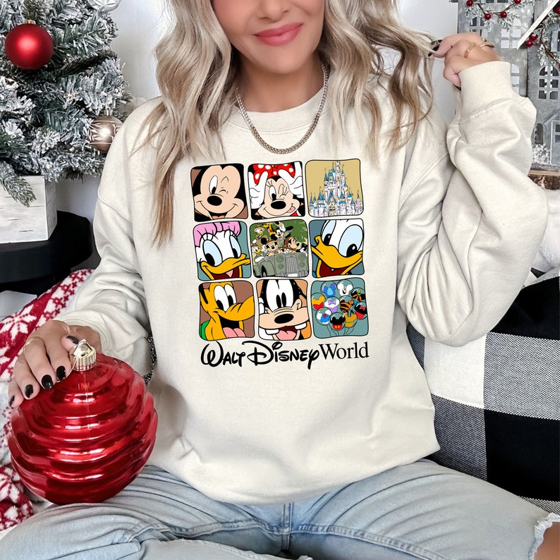 Op de afbeelding: Een cr&egrave;mekleurig sweatshirt met een kleurrijke afbeelding van Disney-figuren en de tekst "Walt Disney World".