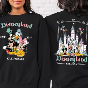 May include: Black sweatshirt with a colourful Disneyland graphic on the front and back. The front features Mickey Mouse, Minnie Mouse, Goofy, Donald Duck, and Pluto. The back features a pastel-coloured illustration of Sleeping Beauty's castle with the text "Disneyland Est. 1955".