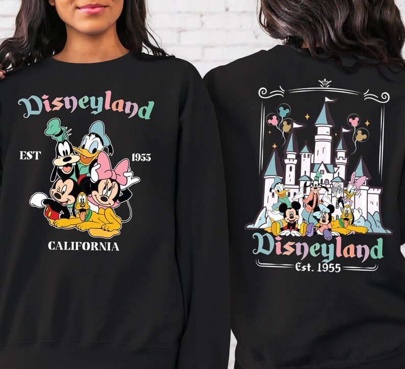 May include: Black sweatshirt with a colourful Disneyland graphic on the front and back. The front features Mickey Mouse, Minnie Mouse, Goofy, Donald Duck, and Pluto. The back features a pastel-coloured illustration of Sleeping Beauty's castle with the text "Disneyland Est. 1955".