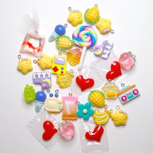 May include: A collection of colourful charm pendants featuring various themes, including food, animals, and electronics. The charms are made of resin and have a glossy finish. They are perfect for adding a touch of whimsy to jewellery, keyrings, or other crafts.