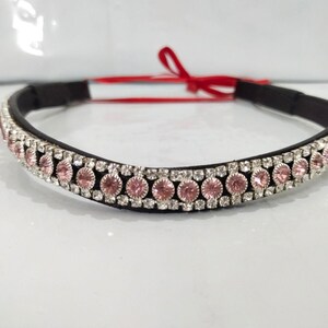 May include: A black leather browband with a row of pink and clear rhinestones.