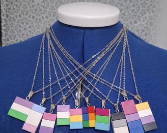 May include: A set of 10 necklaces with different colored Lego brick pendants. Each pendant is made of four stacked bricks in various colors, including green, white, pink, blue, yellow, red, purple, black, and gray.