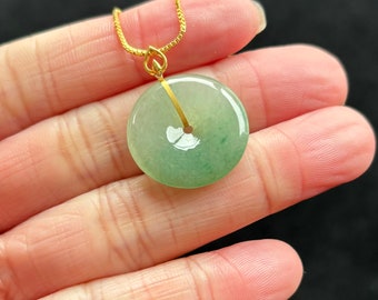 Op de afbeelding: Een groene jade hanger in de vorm van een cirkel met een gouden ketting. De hanger ligt op een hand.