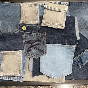 May include: A patchwork design composed of various denim pieces, including pockets and fabric swatches. The denim shades range from light blue to dark indigo, with some gray accents. A black frame surrounds the denim collage.