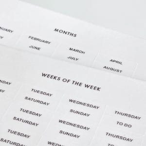 Può includere: Un foglio di etichette adesive bianche con testo stampato in nero. Le etichette sono organizzate in sezioni intitolate MONTHS, che includono da gennaio ad agosto, e WEEKS OF THE WEEK, con i giorni da lunedì a domenica e la scritta TO DO.